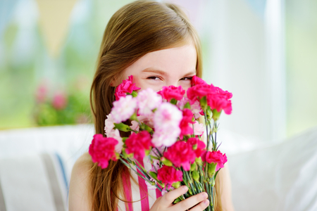 Adorable smiling little girl holding flowers for her mom on mother's dayの写真素材