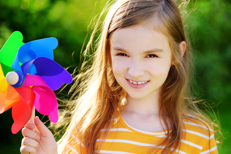 Adorable little girl holding colorful toy pinwheel on warm and sunny summer dayの写真素材