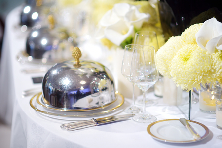 Beautiful table setting with crockery and flowers for a party, wedding reception or other festive event. Glassware and cutlery for catered event dinner.の写真素材