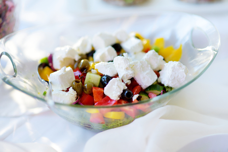 Delicious vegetables and goat cheese salad served on a party or wedding reception. Plates with assorted fancy finger food snacks on an event party or dinner.の写真素材