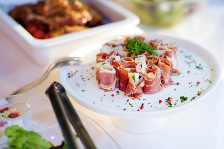 Delicious ham rolls with vegetables served on a party or wedding reception. Plates with assorted fancy finger food snacks on an event party or dinner.の写真素材