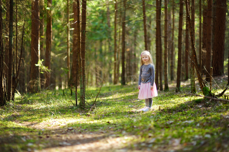 Cute little girl having fun during forest hike on beautiful spring day. Active family leisure with kids.の写真素材