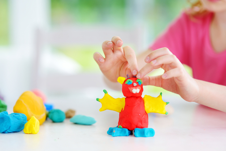 Cute little girl having fun with colorful modeling clay at a daycare. Creative kid molding at home. Child play with plasticine or dough.の写真素材