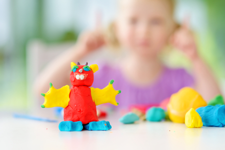 Cute little girl having fun with colorful modeling clay at a daycare. Creative kid molding at home. Child play with plasticine or dough.の写真素材