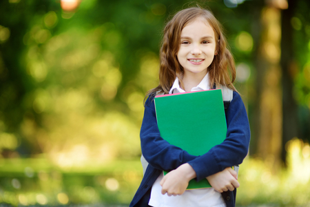 Adorable little schoolgirl studying outdoors on bright autumn day. Young student doing her homework. Education for small kids. Back to school concept.の写真素材