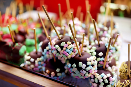 Apples dip in chocolate icing and small marshmallows sold on Christmas market. Candies, sweets and desserts on Xmas time. Winter holidays outdoors.の写真素材