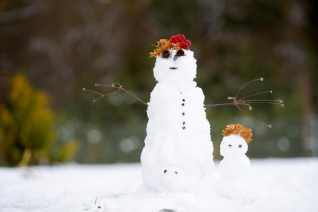 Two tiny little snowmen on beautiful winter day. Winter activities for children and adult.の写真素材