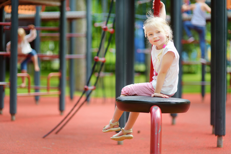 Cute little girl having fun on a playground outdoors in summer. Sport activities for kids.の写真素材