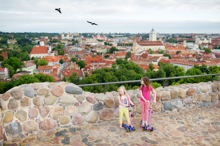 Cute little girls enjoying a view of Vilnius city from the Gediminas hill. Exploring tourist attractions with kids.の写真素材