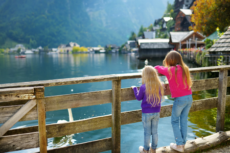 Two little girls enjoying the scenic view of Hallstatt lakeside town in the Austrian Alps in beautiful evening light on beautiful day in autumnの写真素材