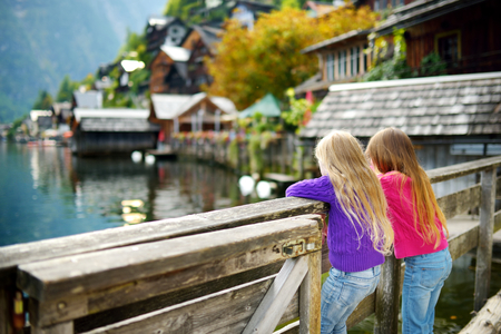 Two little girls enjoying the scenic view of Hallstatt lakeside town in the Austrian Alps in beautiful evening light on beautiful day in autumnの写真素材