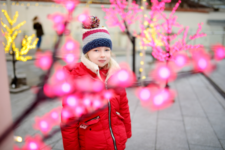 Adorable little girl having fun on beautiful Christmas time. Cute child having a walk in winter town. Winter activities for kids.の写真素材