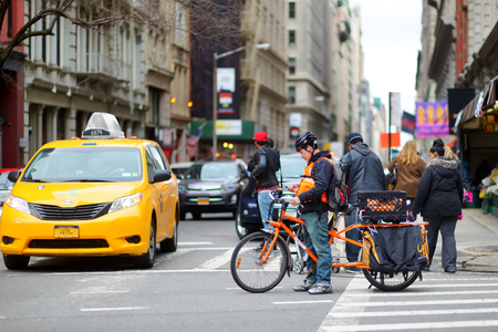 NEW YORK - MARCH 16, 2015: Cyclist and yellow taxi cabs rushing on busy streets of downtown Manhattan.のeditorial素材