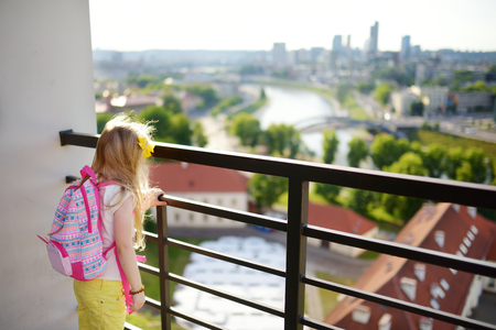 Cute little girl enjoying a view of Vilnius city from the Gediminas hill. Exploring tourist attractions with kids. Vilnius, Lithuania.の写真素材