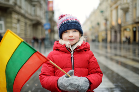 Cute little girl celebrating Lithuanian Independence Day holding tricolor Lithuanian flag in Vilnius, Lithuaniaの写真素材