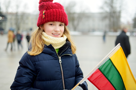 Cute little girl celebrating Lithuanian Independence Day holding tricolor Lithuanian flag in Vilnius, Lithuaniaの写真素材