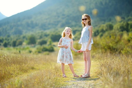 Two cute young sisters laughing and hugging on warm and sunny summer day during family vacations in Peloponnese, Greeceの写真素材