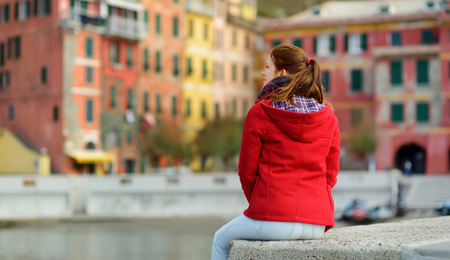 Young female tourist enjoying the view of Vernazza, one of the five centuries-old villages of Cinque Terre, located on rugged northwest coast of Italian Riviera, Liguria, Italy. Traveling off season.の写真素材