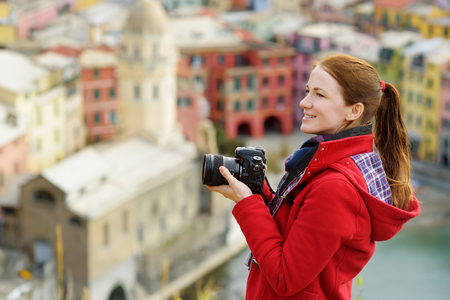 Young female tourist enjoying the view of Vernazza, one of the five centuries-old villages of Cinque Terre, located on rugged northwest coast of Italian Riviera, Liguria, Italy. Traveling off season.の写真素材