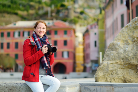 Young female tourist enjoying the view of Vernazza, one of the five centuries-old villages of Cinque Terre, located on rugged northwest coast of Italian Riviera, Liguria, Italy. Traveling off season.の写真素材