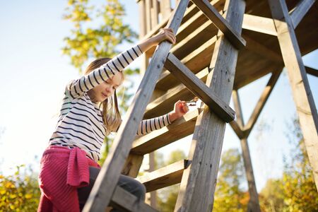 Young girl having fun at observation tower on Tauciuliskes cognitive walking way, leading through beautiful autumn forest to the Tauciliuskes lake, located near Vilnius, Lithiania.の写真素材