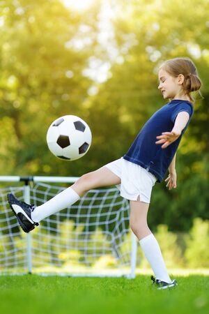 Cute little soccer player having fun playing a soccer game on sunny summer day. Sport activities for children. Kids in sports uniform.の写真素材