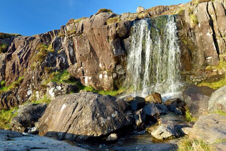 Small waterfall at the Conor Pass, one of the highest Irish mountain passes served by an asphalted...