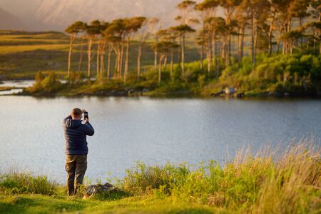 Tourist admiring the view of Twelve Pines Island, standing on a gorgeous background formed by the...