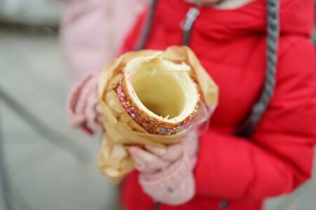 Cute young girl eating Czech trdelnik on traditional Christmas fair in Vilnius, Lithuania. Child...