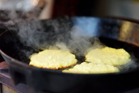Delicious potato pancakes being fried on traditional spring market in Vilnius, Lithuania. Variety tasty street food on Easter fair.の写真素材