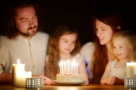 Cute sever year old girl making a wish before blowing candles on her birthday cake. Child celebrating her birhday. Birthday traditions.の写真素材