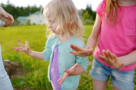 Two cute little sisters helping their mother to plant seedlings in a garden. Children taking part in outdoor household chores. Active family leisure at spring.の写真素材