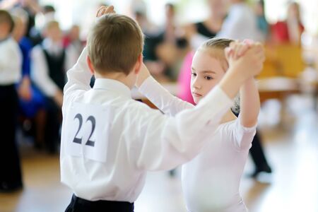 Happy young children participating in dance competition at dancing school. Boy and girl dressed in...