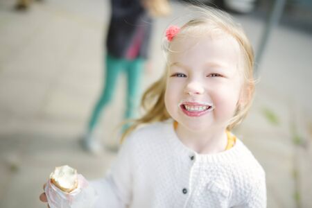 Cute girl eating tasty fresh ice cream outdoors on warm sunny summer day. Children eating sweets....