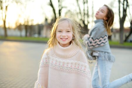 Two cute young sisters having fun together on beautiful spring day in a city. Active family leisure with kids. Family fun outdoors.の写真素材