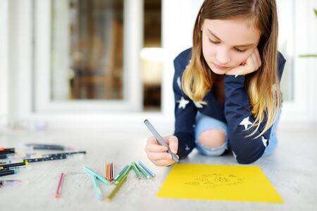 Young girl drawing with colorful pencils at home. Creative kid doing crafts. Education and distance learning for kids. Homeschooling during quarantine. Stay at home entertainment.の写真素材