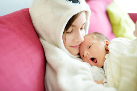 Cute big sister admiring her newborn brother. Adorable teenage girl holding her new baby boy...