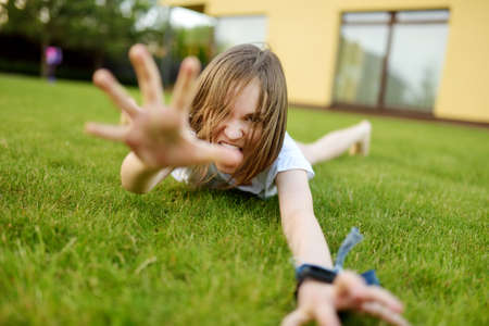 Funny young girl having fun on a grass on the backyard on sunny summer evening. Summer activities...