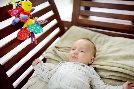 Cute three months old baby boy playing with his colourful toys outdoor. Baby during playtime.の写真素材