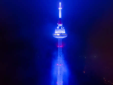 VILNIUS, LITHUANIA - FEBRUARY 11, 2020: Aerial night foggy view of Vilnius TV tower illuminated in blue for 30th Anniversary of the first commercial radio station M1.のeditorial素材
