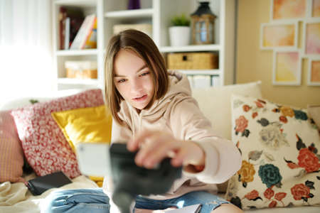 Beautiful teenage girl recording video blog with her smartphone. Young vlogger shooting vlog at...