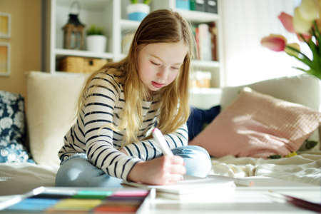 Cute young girl writing letter at home. Child doing her homework in her room. Education for kids
