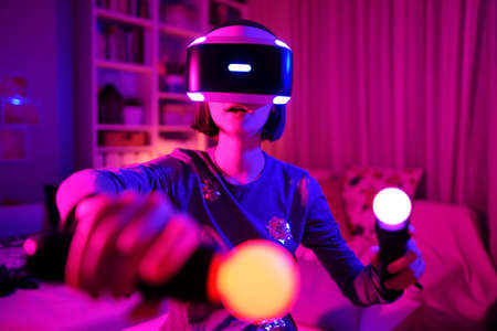 Pretty teenage girl wearing virtual reality headset in a dark room. Cute teen using VR glasses to play a game. Child in virtual augmented reality helmet. Future technology concept.の写真素材