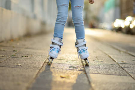Young girl learning to roller skate on beautiful summer day on a street. Child enjoying roller...