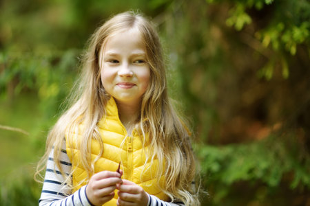 Cute young girl having fun during forest hike on beautiful summer day. Child exploring nature. Active family leisure with kids.の写真素材
