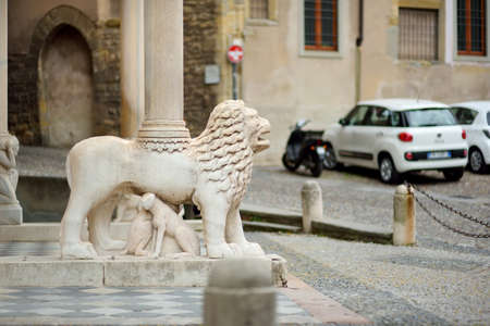 Beautiful stone pillar with a sculpture of a lion on beautiful medieval street of Bergamo city, Lombardy, Italy.の写真素材