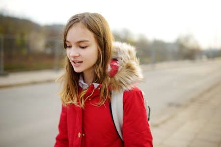 Cute young girl with a backpack heading to school on cold winter morningの写真素材