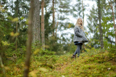 Cute young girl having fun on beautiful autumn day in a forest. Active family leisure with kids. Family fun outdoors.の写真素材