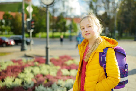 Cute young girl with a backpack heading to school on cold autumn morningの写真素材
