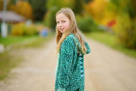 Cute young girl having fun on beautiful sunny autumn day. Active family leisure with kids. Family fun outdoors.の写真素材